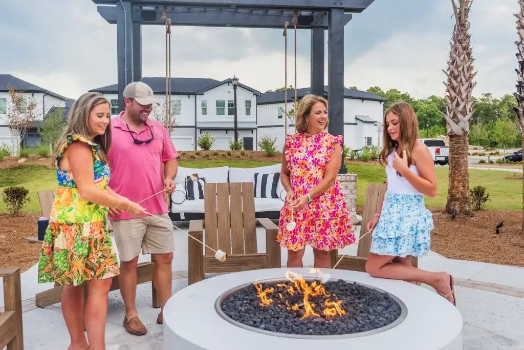 Residents enjoying the outdoor fire pit at The Lively Grande Dunes, roasting marshmallows and socializing in a cozy lounge area.