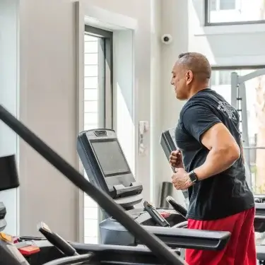 Fitness center at The Lively Grande Dunes in Myrtle Beach with a resident using a professional treadmill.
