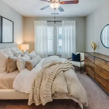 Upscale Myrtle Beach apartment bedroom with large windows and a ceiling fan at The Lively Grande Dunes.